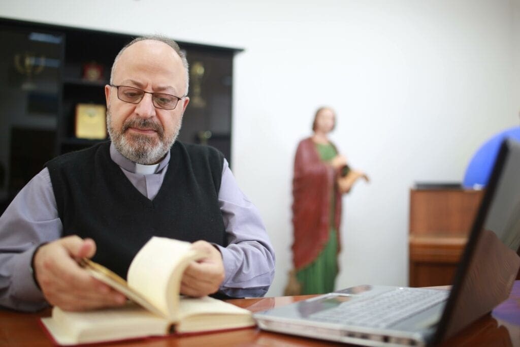 Father André Ghaoui thumbs through a theology book in the library of St. John the Apostle Seminary in Harissa, Lebanon.