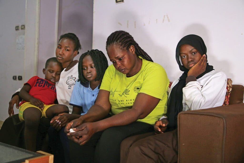 a family of African refugees sits on a couch in their home in Egypt.