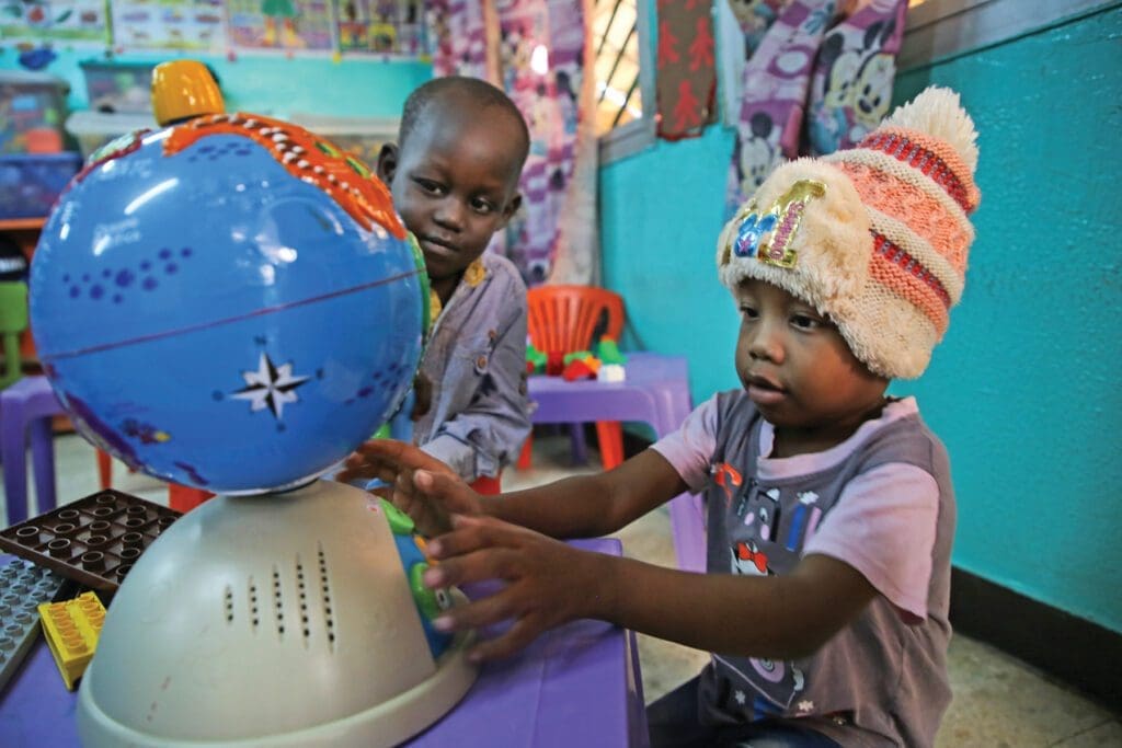 two children play with a globe.