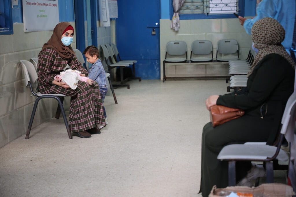 a woman sits with her child in a nearly empty waiting room.