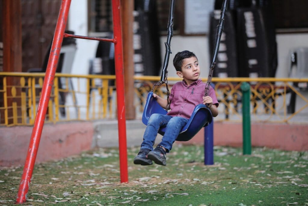 a boy rides a swing outside.