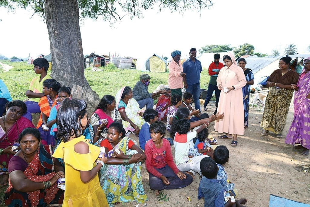 nuns distribute supplies to villagers gathered outside in India.