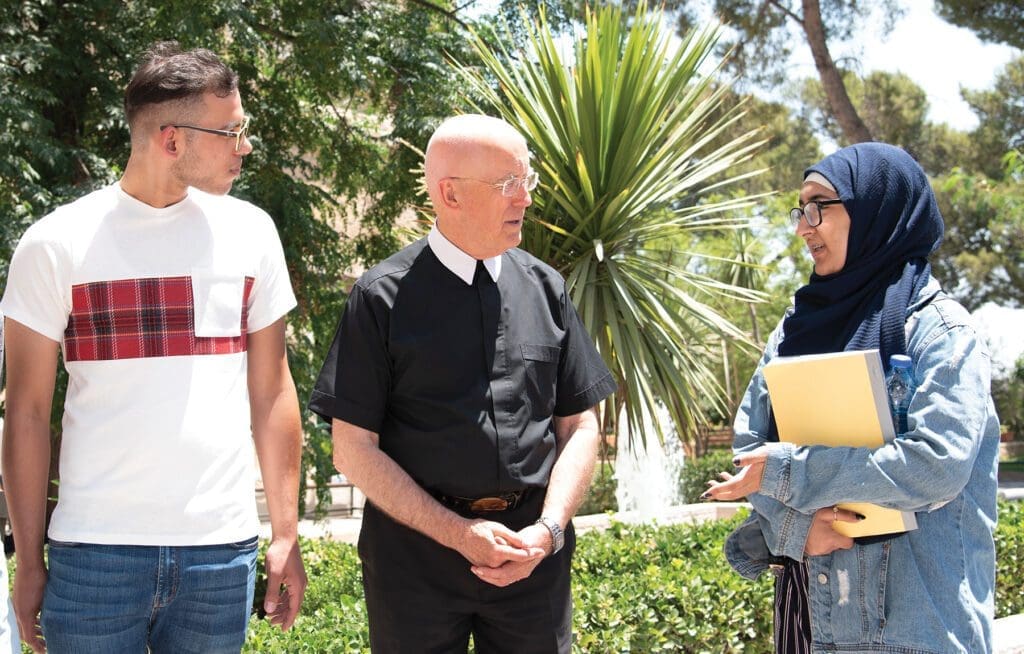 a religious brother dialogues with students outside.