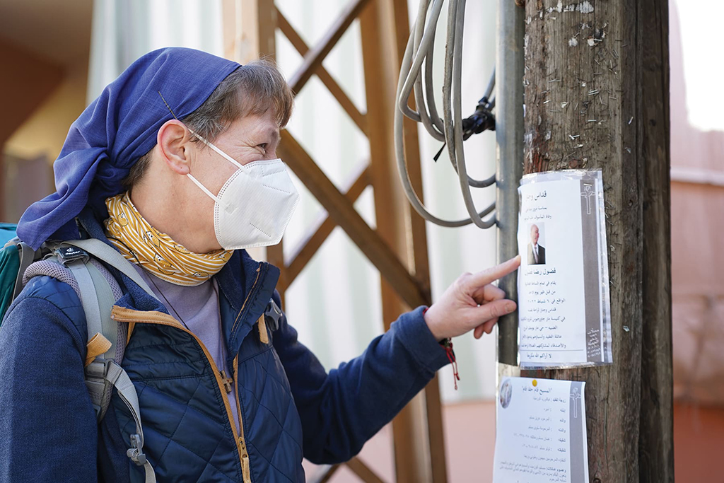 A nun's eyes reveal her smile from under her mask as she reads a flyer.