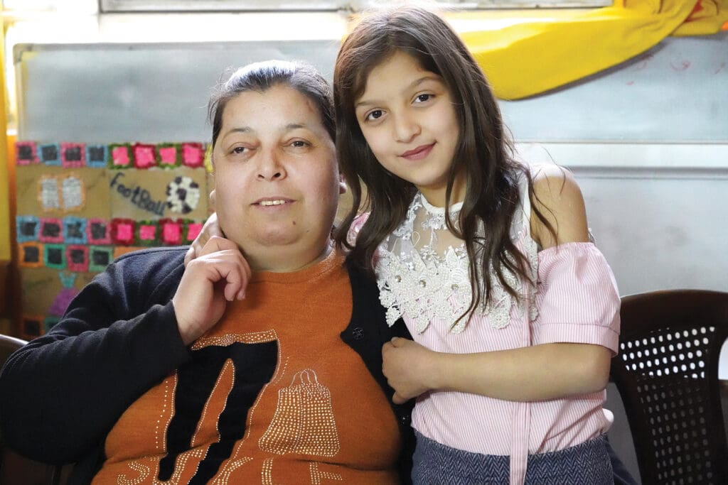 A daughter and mother pose together.