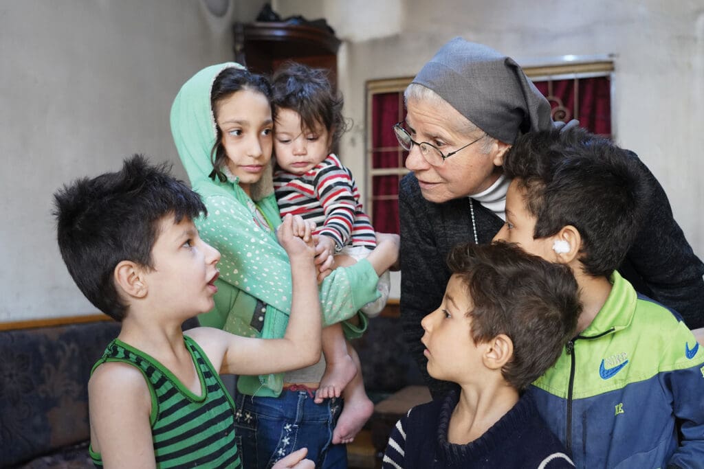 A nun standing amongst a group of children.