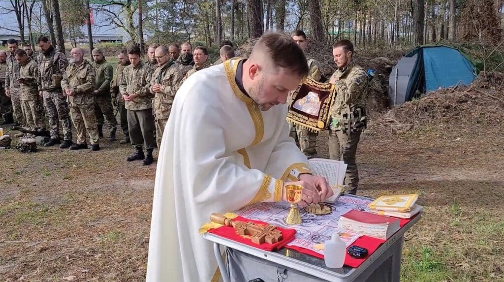 A military chaplain celebrates mass with a row of Ukrainian soldiers behind him