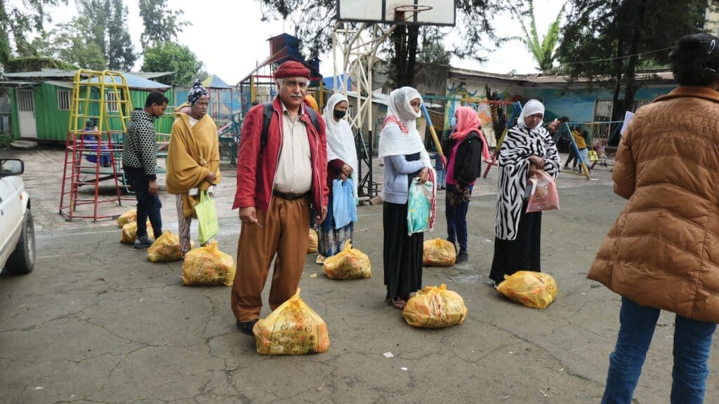 A group of refugees stand with yellow food packages