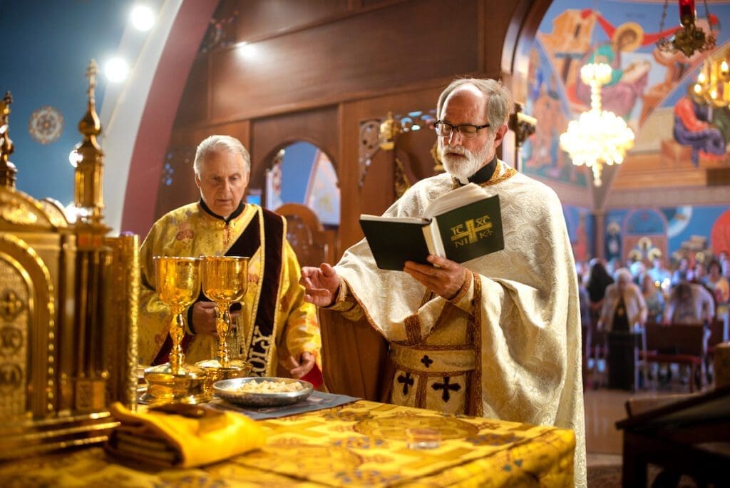 Priest blesses the gifts while deacon observes, at a parish in Chicago.