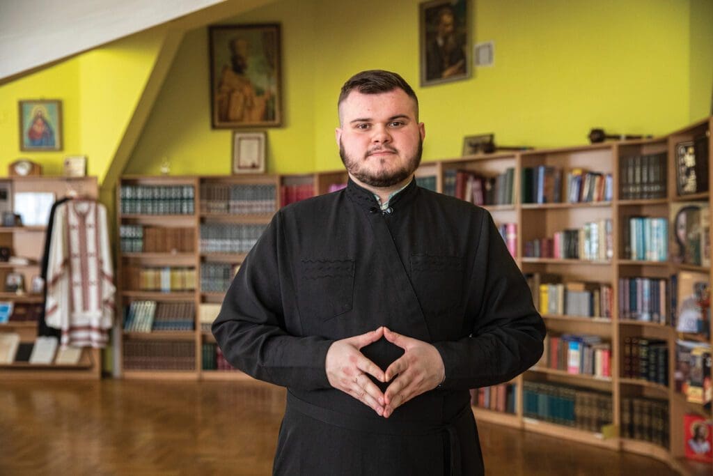 A seminarian poses in the library of his seminary