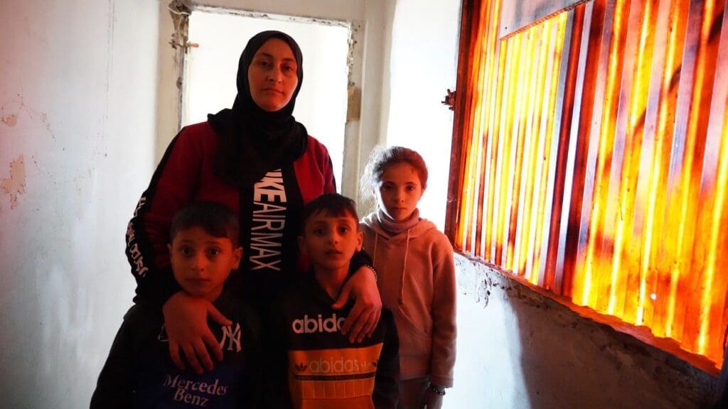 A woman and her three children are illuminated by light coming in through the window