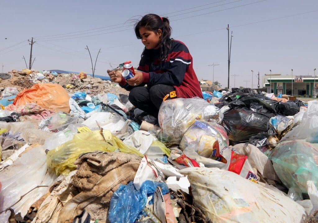 A girl collects cans from a garbage dump in Iraq.