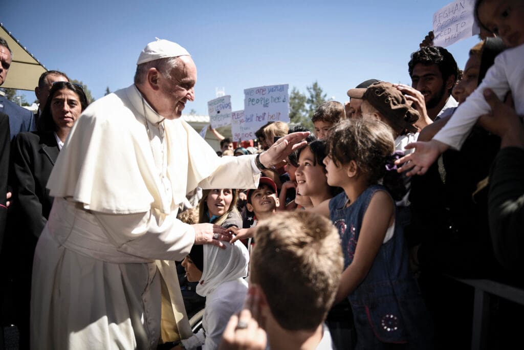 Pope Francis salutes children on a street.