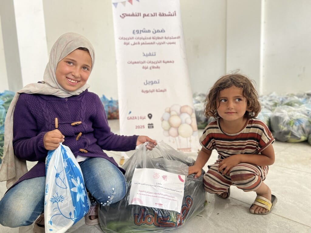Two smiling girls, one wearing a hijab.