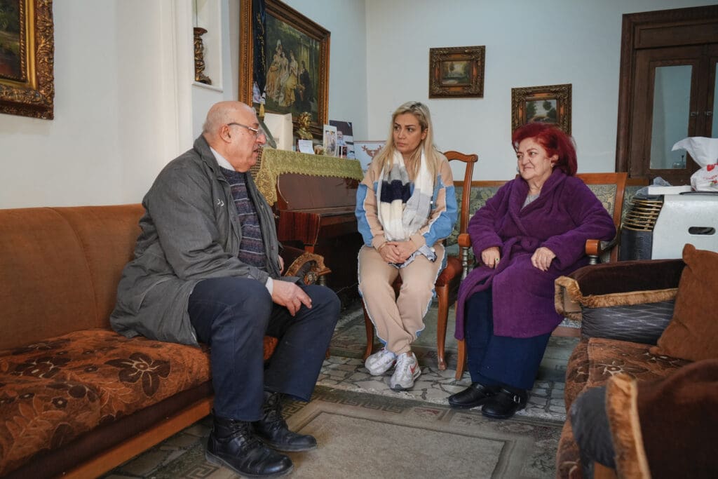 A man and two women sitting in a living room.