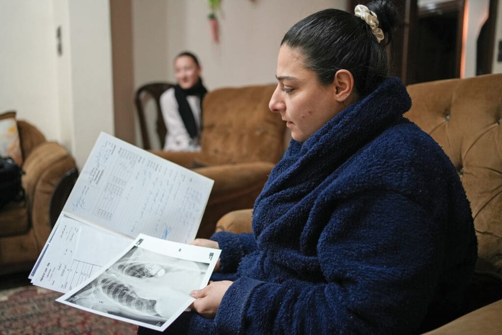 Woman sitting on a couch reviews her x-rays.
