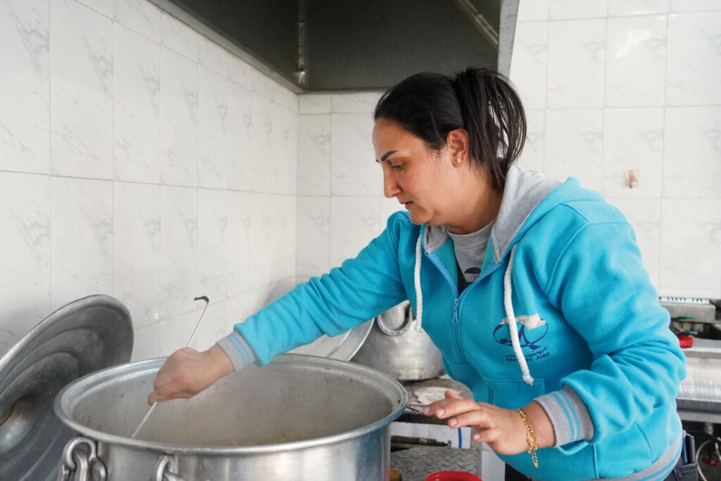A woman cooking on a big pot.