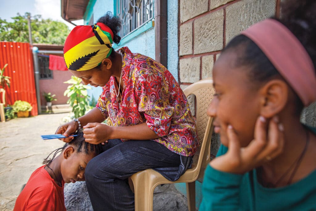 A woman braids the hair of a girl.