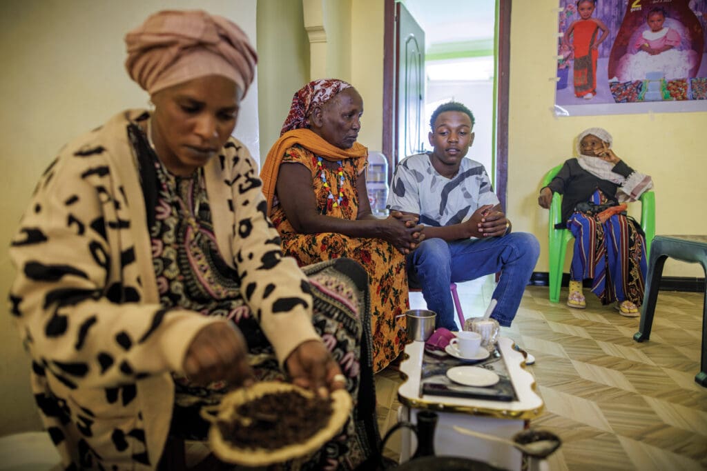 Young man watches women preparing coffee.