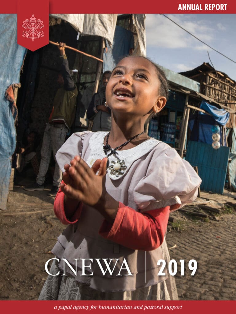 Cover image of the annual report features a little girl on a street, smiling looking up with her hands together as in prayer..