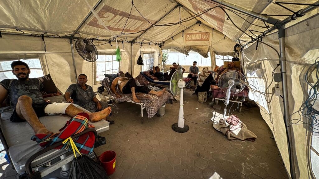 A hospital tent with several wounded people.