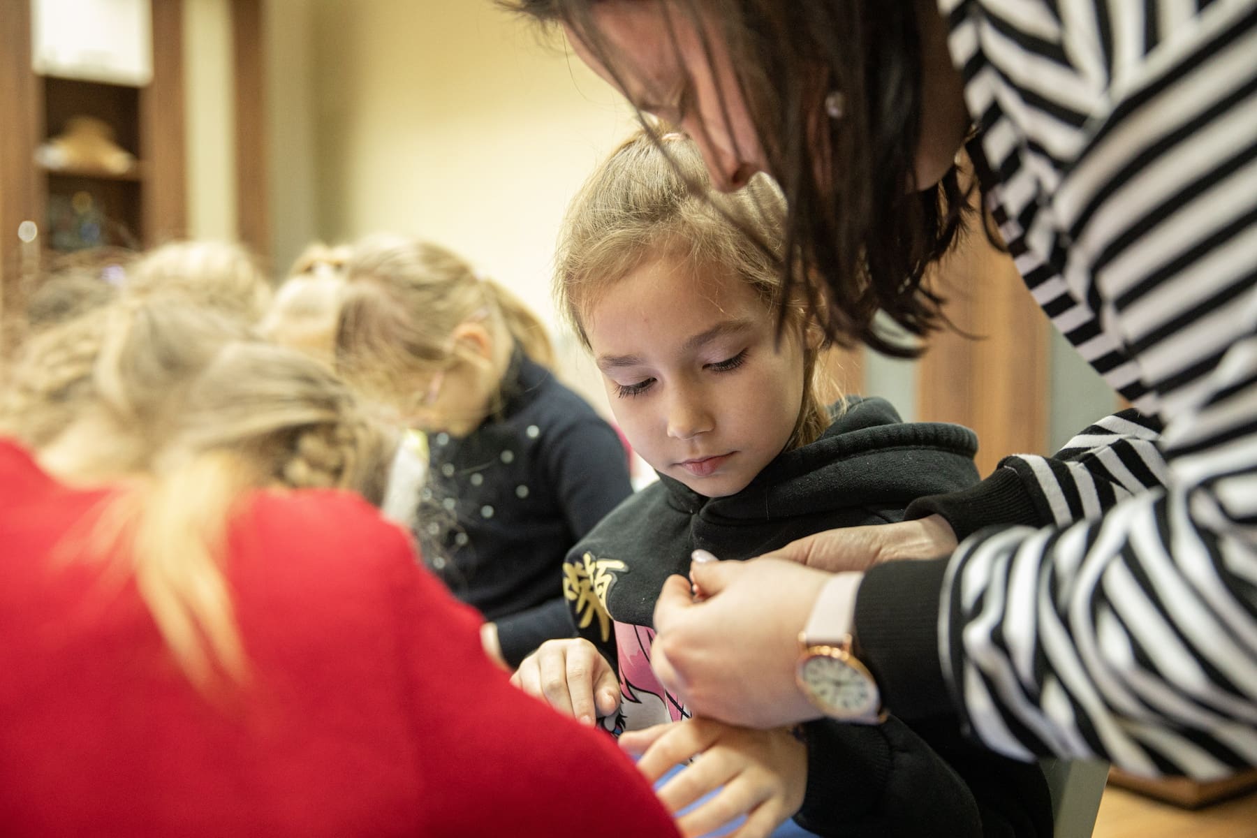 Close up of a woman showing a girl how to make a craft.