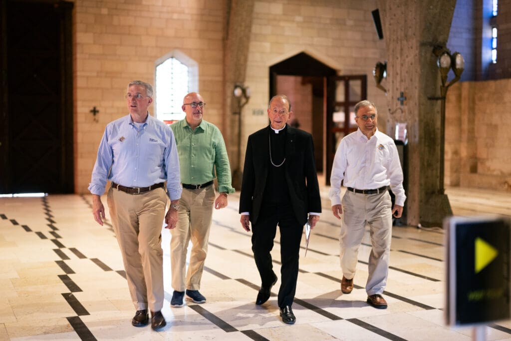 A priest and four men walk in a church.