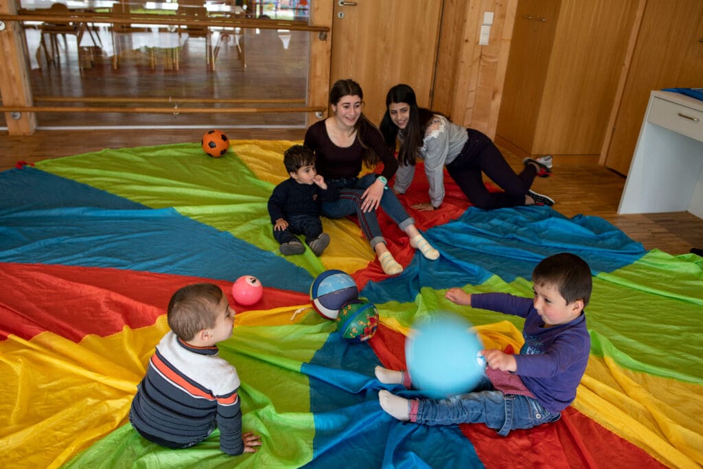 Two teen girls are playing with three infants.
