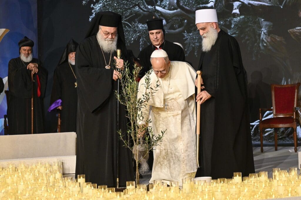 Pope Leo XIV waters an olive tree after he and other religious leaders planted it during an ecumenical and interreligious meeting.