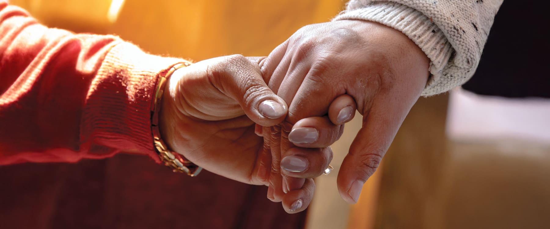Close up of two hands from different people, holding each other.