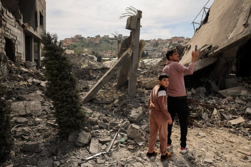 A man and a boy look at a destroyed building.