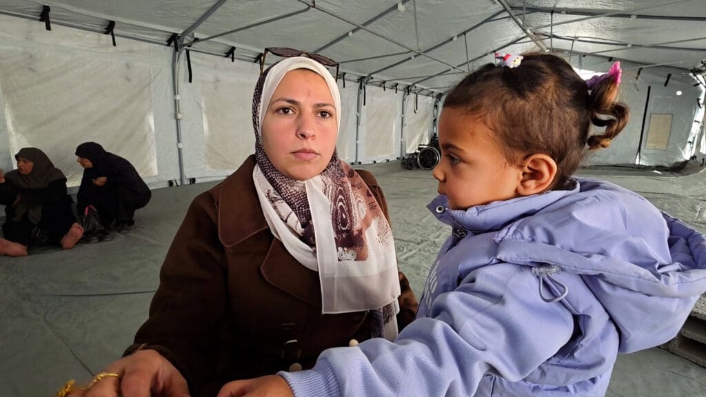 A woman is seen under a big white tent with a child.