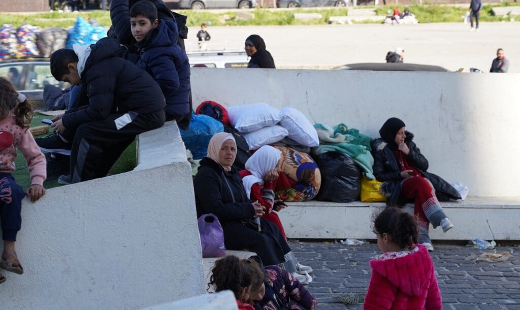 People seeing on a street next to bags.