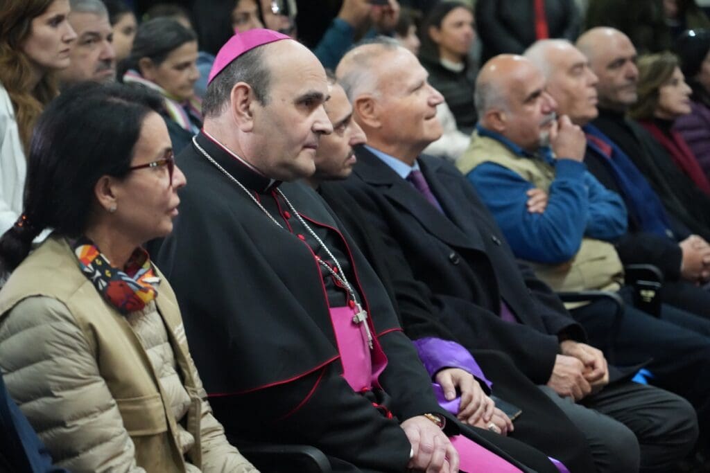 Apostolic Nuncio Paolo Borgia sitting among other people in a conference room.