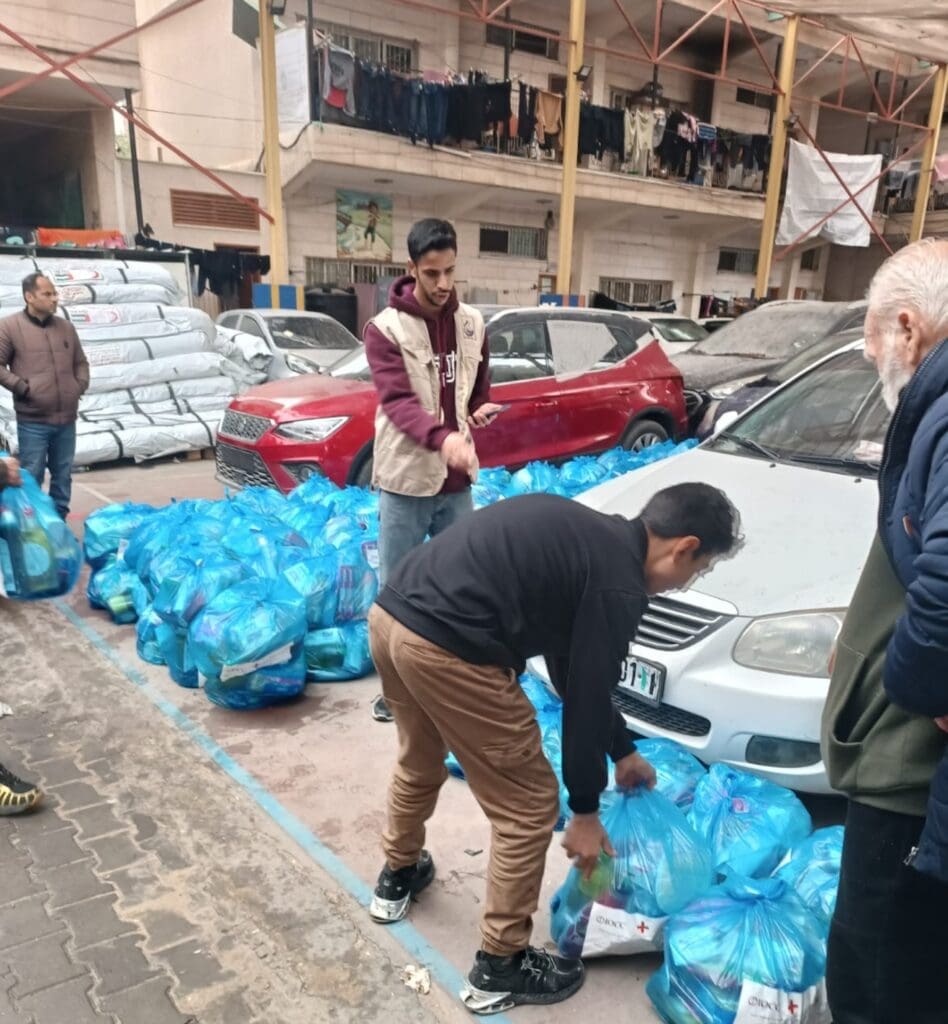 Men organizing blue bags next to cars parked.