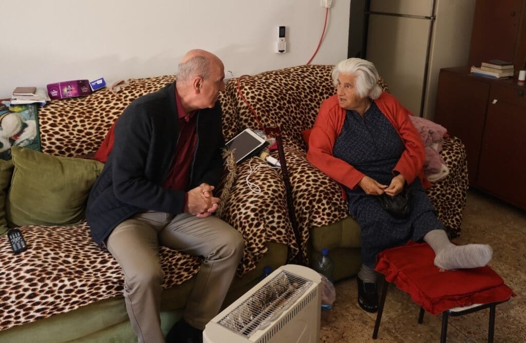 A man sits on a couch next to an elderly woman.