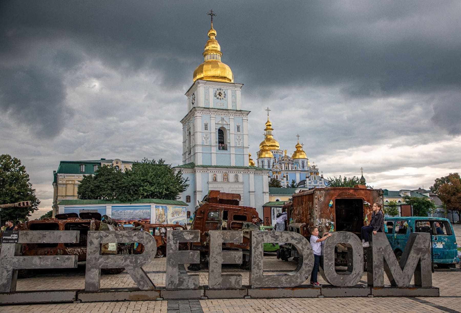 An open-air exhibit of destroyed Russian military equipment in front of a church.