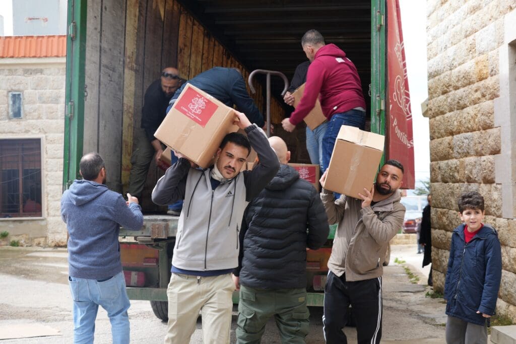 A group of men unloading boxes from a truck on a street in Lebanon.