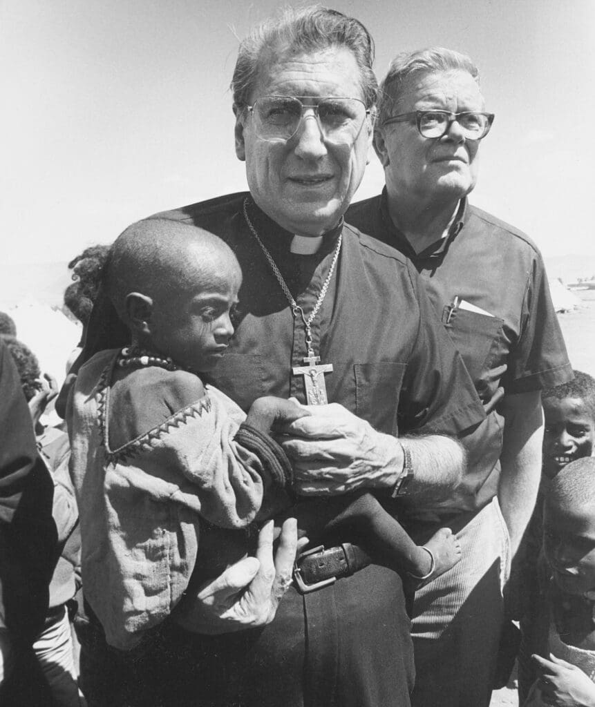 A priest carrying a malnourished child.