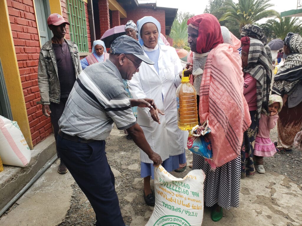 A man gives a bag of rice and a gallon of oil to a woman on a street.