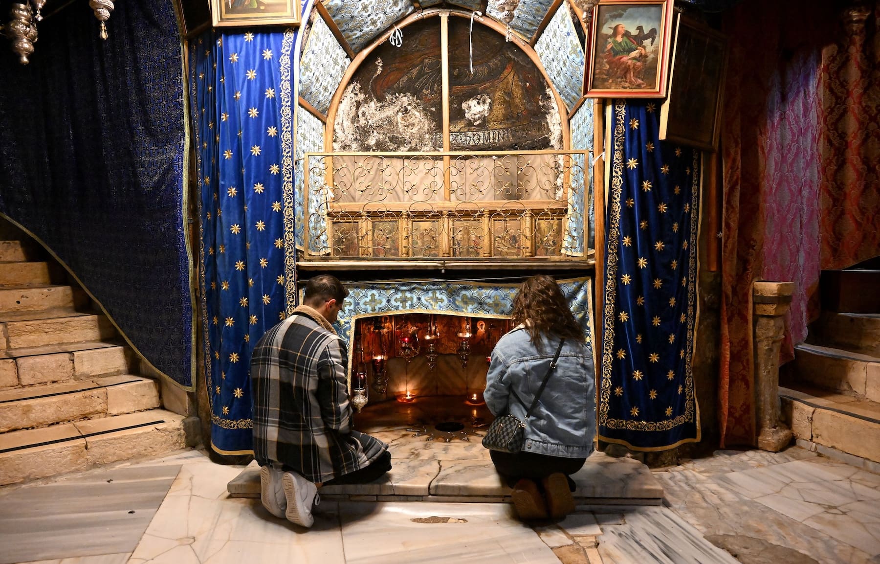 A man and a woman pray in the grotto of the sixth-century Church of the Nativity, in Bethlehem.